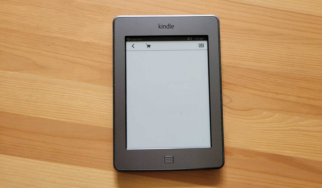 Ein Kindle eBook-Reader im Test liegt mit weißer Anzeige auf einer Holzoberfläche.