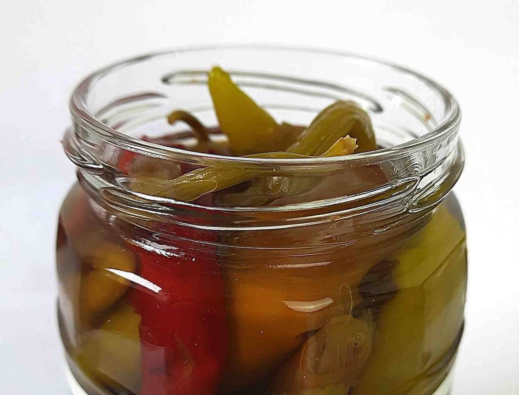 Getestet: Detailansicht von mehreren eingelegten Peperoni im Glas.