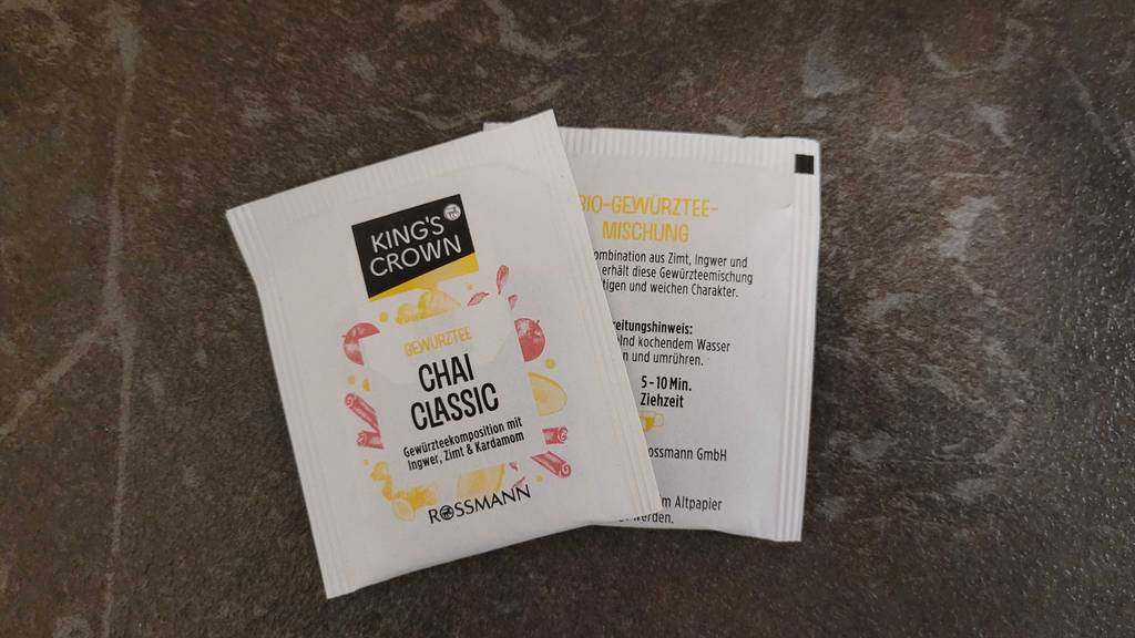 Chai-Tee-Test: Zwei weiße Beutelpackungen Tee liegen nebeneinander auf einer dunklen Oberfläche.