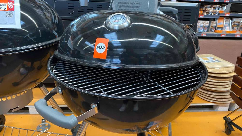 Ein Kugelgrill, 57 cm, mit halb geöffnetem Deckel im Test.