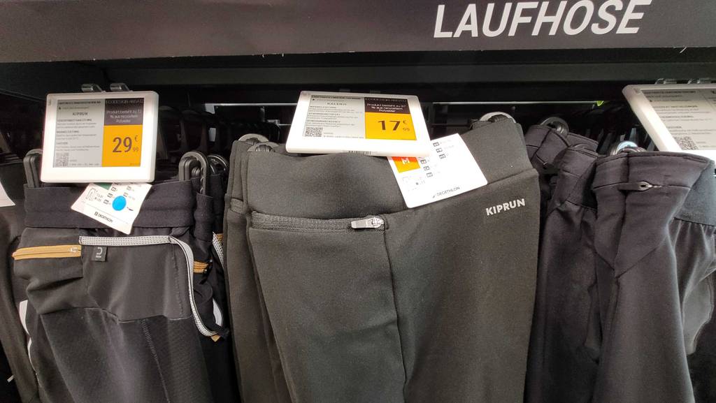 Thermo-Laufhose-Herren-Test: Die Nahaufnahme einer grauen, getesteten Thermo-Laufhose für Herren zusammen mit weiteren langen Hosen an einem Verkaufsregal hängend.