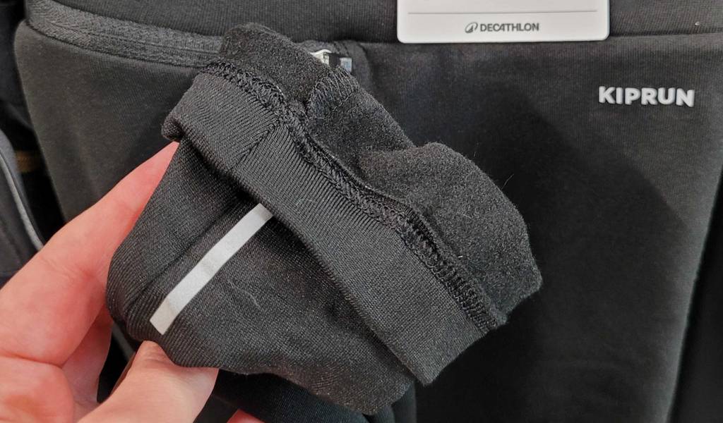 Thermo-Laufhose-Herren-Test: Die Nahaufnahme einer grauen, getesteten Thermo-Laufhose für Herren zusammen mit weiteren langen Hosen an einem Verkaufsregal hängend.