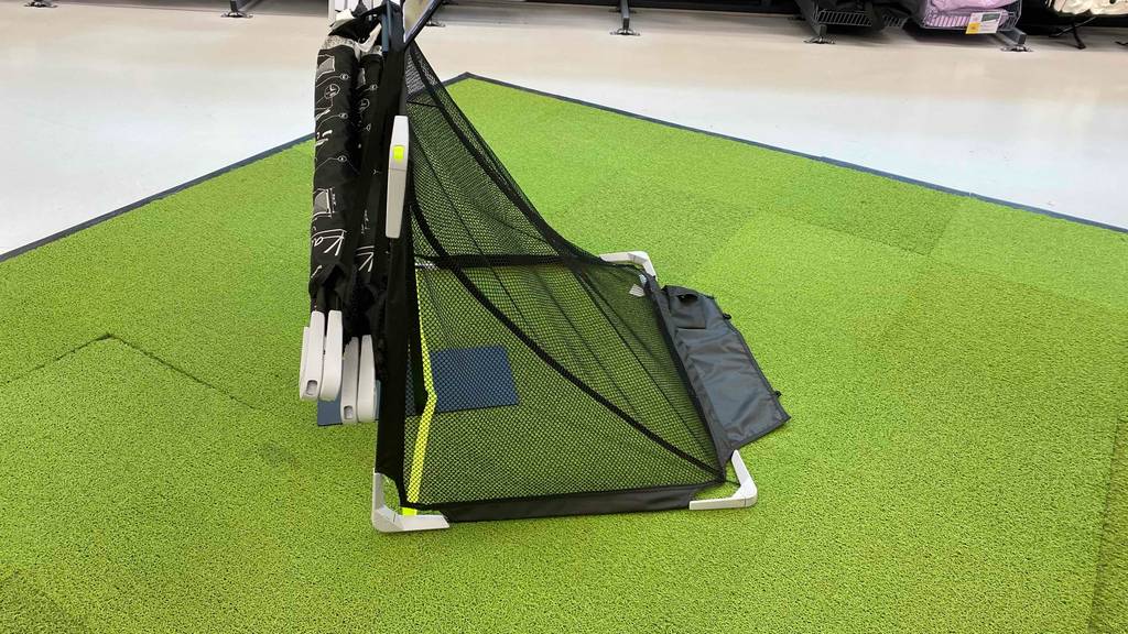 Seitenansicht eines auf Kunstrasen ausgestellten Kinder-Fußballtors im Test, an dem weitere verpackte Modelle des gleichen Typs hängen.