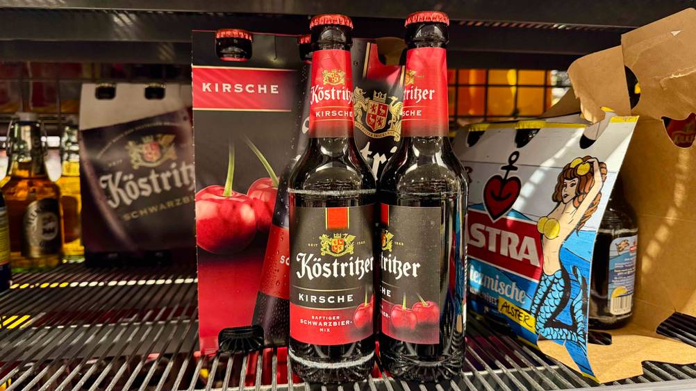 Mehrere Flaschen des getesteten Kirschbiers in einem Verkaufsregal neben anderen Produkten.