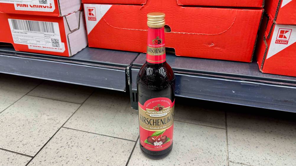Kirschlikör im Test: Eine Flasche von schräg oben vor einem Verkaufsregal.