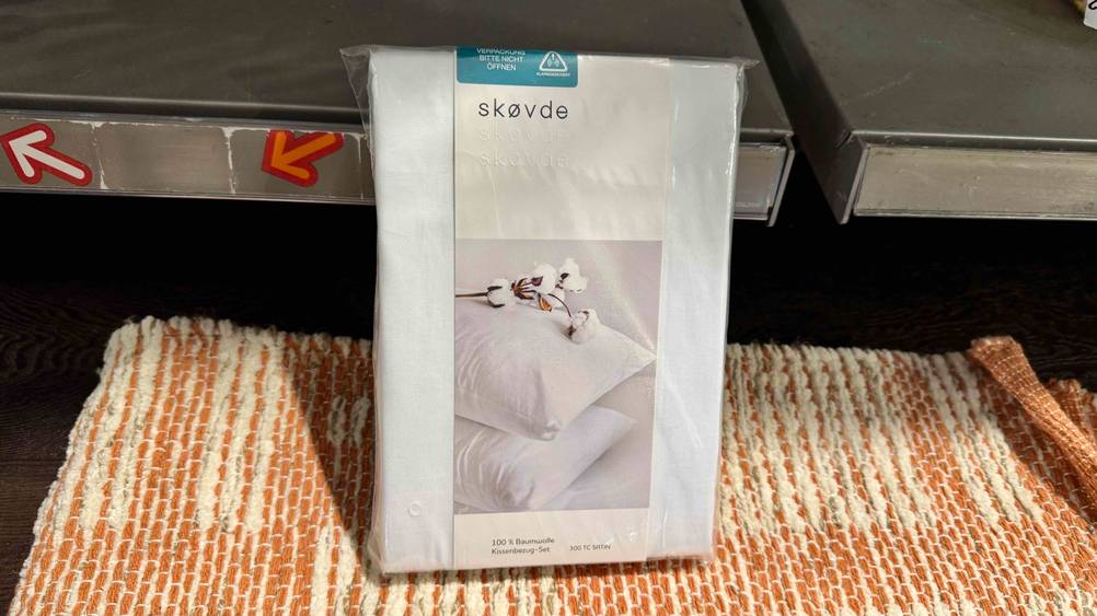 Eine Packung des getesteten Kissenbezugs lehnt an einem Regalbrett.