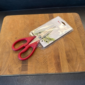 Die Kitchenaid-Allzweck-Küchenschere liegt in ihrer Verpackung auf einer Holzplatte