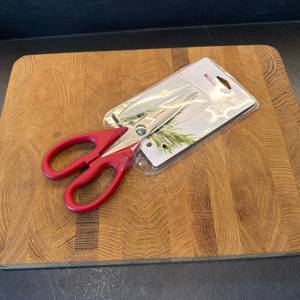 Die Kitchenaid-Allzweck-Küchenschere liegt in ihrer Verpackung auf einer Holzplatte