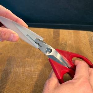 Eine Hand zieht einen Schutz von der Kitchenaid-Allzweck-Küchenschere