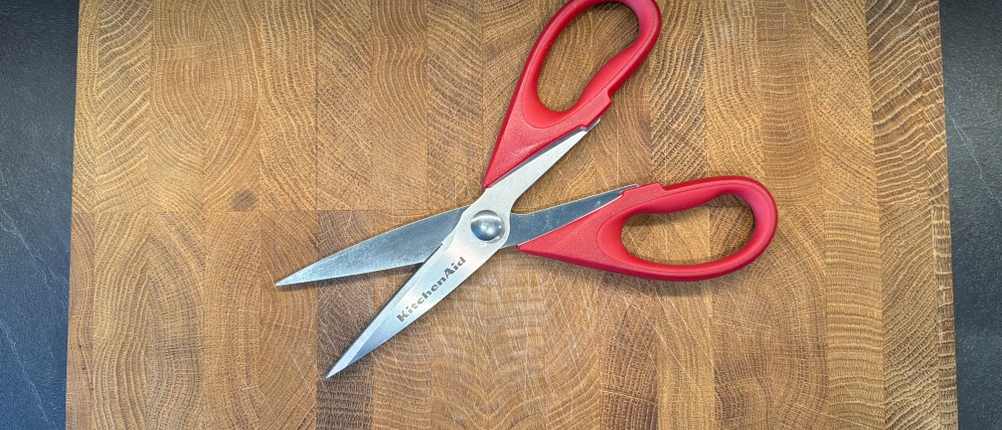 Die Kitchenaid-Allzweck-Küchenschere liegt auf einem Holzbrett