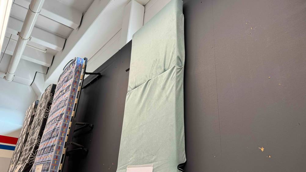An einer Wand hängt ausgestellt eine getestete Klappmatratze.
