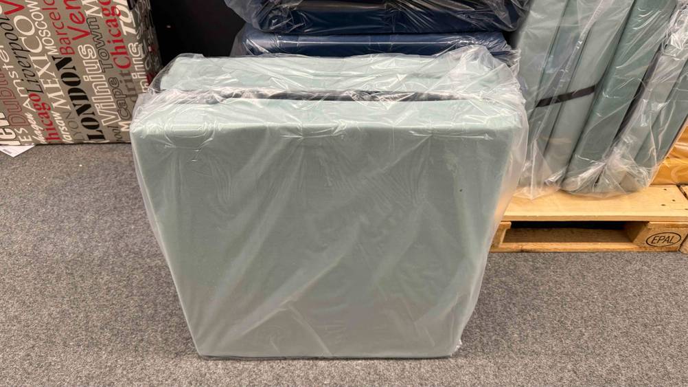 Klappmatratze getestet: Ein verpacktes Produkt von vorne vor einer Holzpalette.