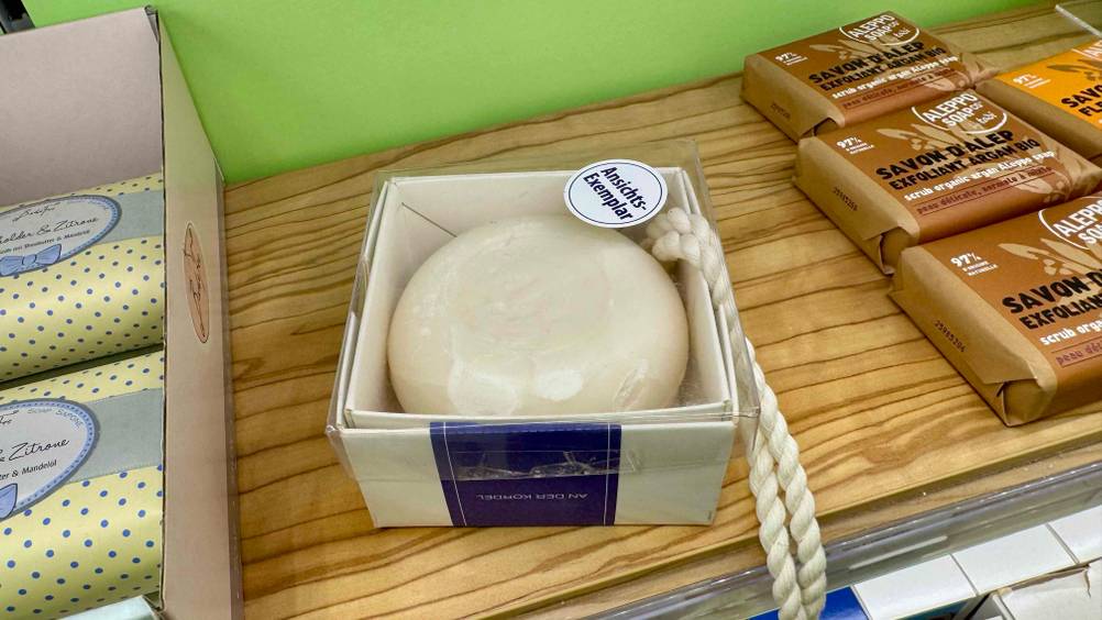 Klar-Seife im Test: Eine verpackte Seife auf einem Holzregal neben anderen Seifen.