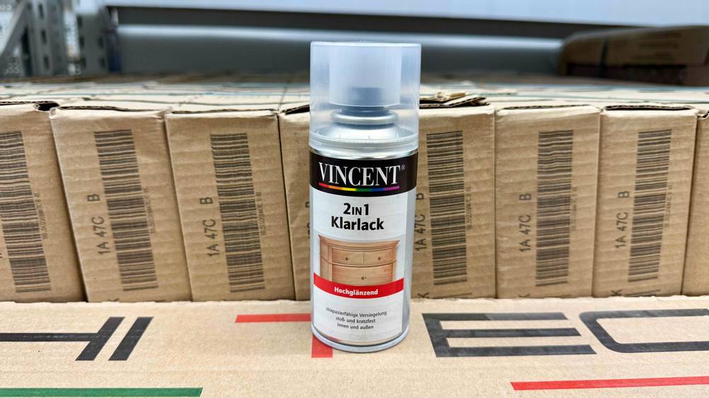 Klarlack-Spray im Test: Eine Dose steht auf mehreren Kartons.