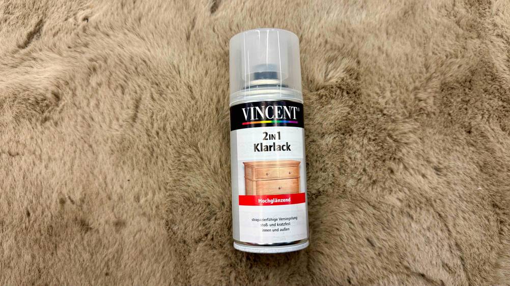 Auf einem Fell liegt eine Dose des getesteten Klarlack-Sprays.