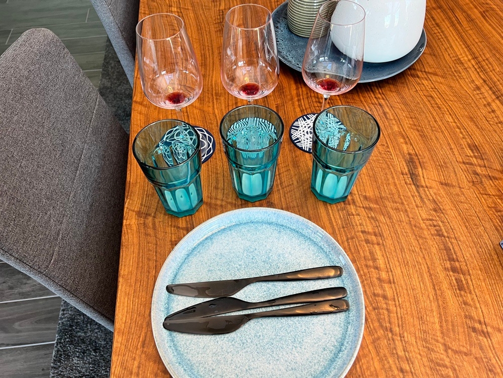 Auf einem Tisch stehen je drei Weingläser mit Wein, Gläser mit Milch und Messer mit Wasser