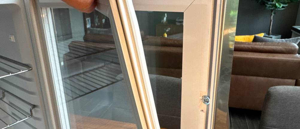 Das Silikon im Rahmen der Tür des Klarstein Beersafe M wird von einer Hand abgelöst.