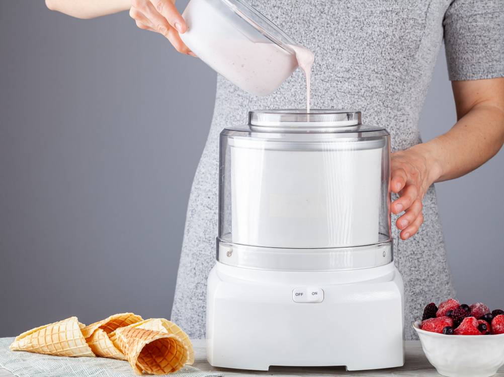 Klarstein-Eismaschine-Test: Eine Frau befüllt eine weiße Eismaschine mit Milch. 