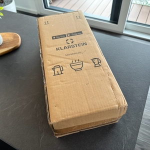 Der zusätzliche Karton des Klarstein Quickstick liegt auf einer Arbeitsplatte