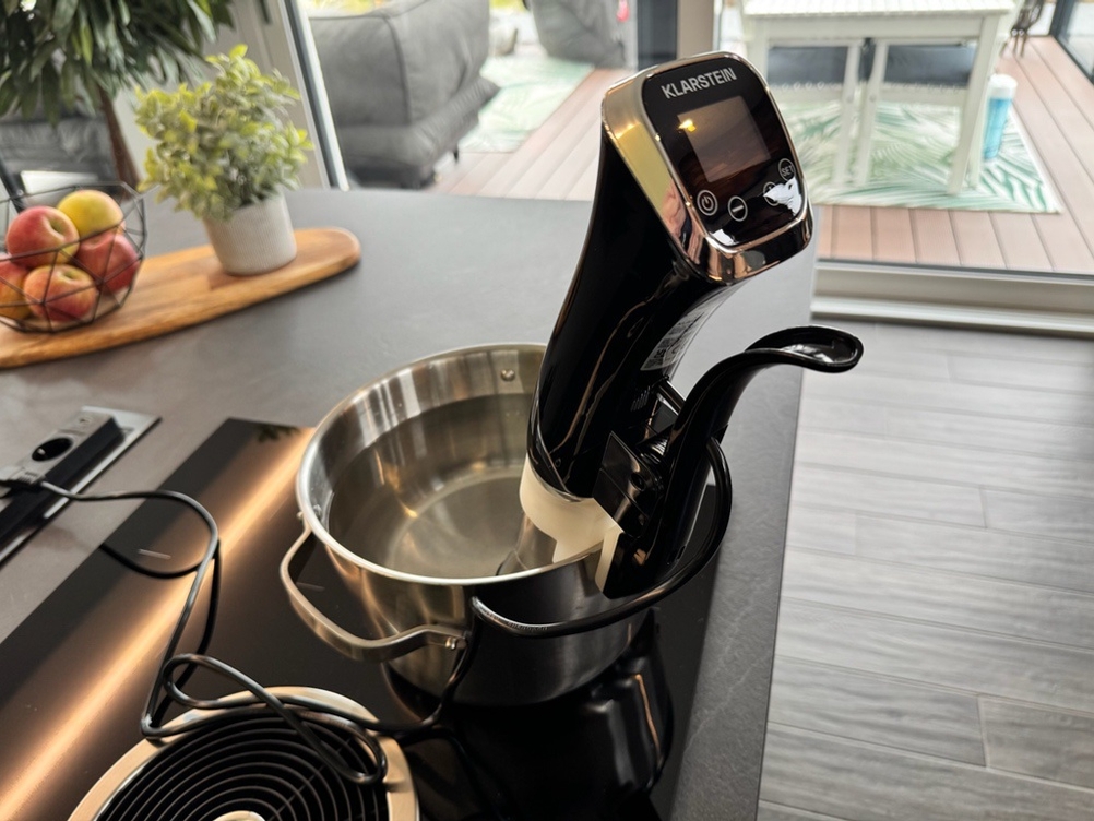 Der ausgeschaltete Klarstein Quickstick hängt in einem Topf mit Wasser