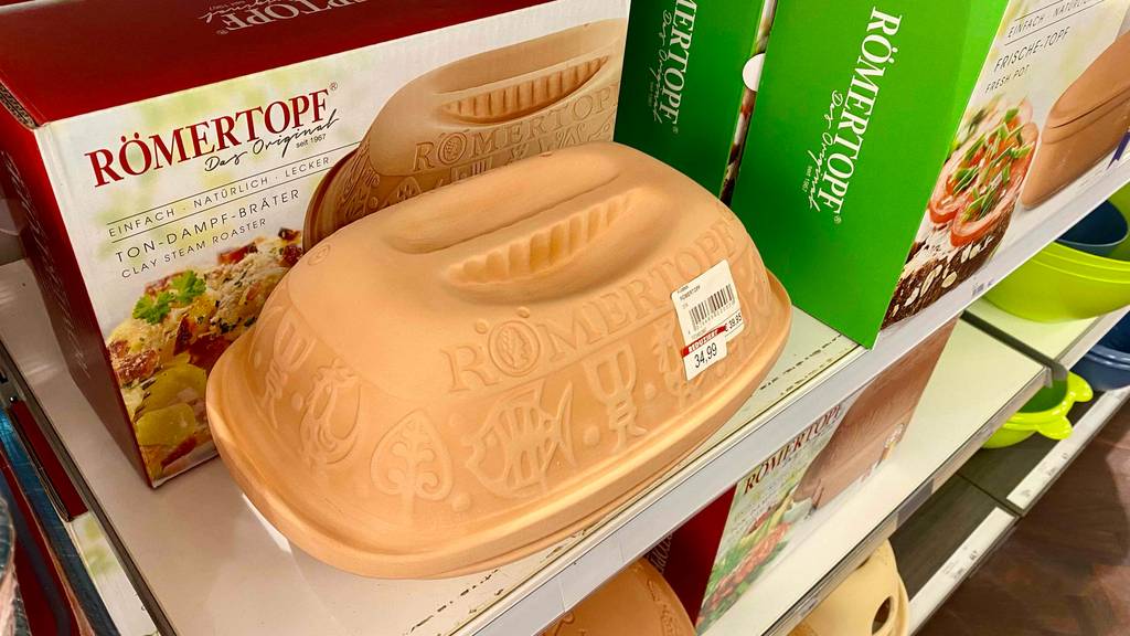 Römertopf-Test: ein geschlossener Klassik-Ton-Römertopf steht vor seiner Originalverpackung und mit Preisetikett auf einem Verkaufsregal neben anderen Modellen.