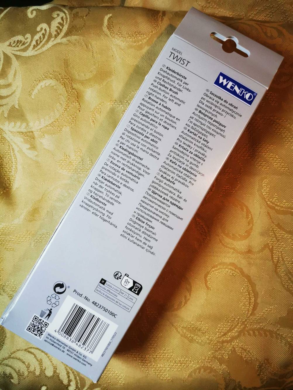 Auf einer gelben Tischdecke liegt die Originalverpackung der getesteten Kleiderbürste mit der Rückseite nach oben.