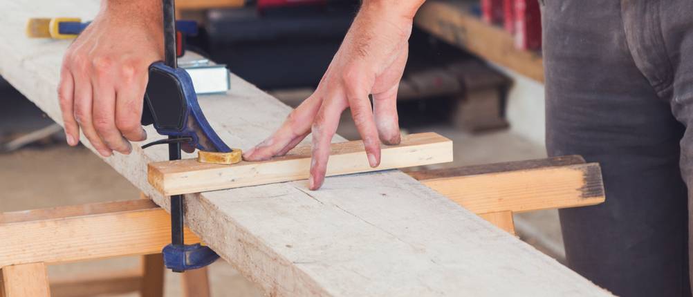 Tischler spannt zwei Holzstücke mit Einhandzwinge ein