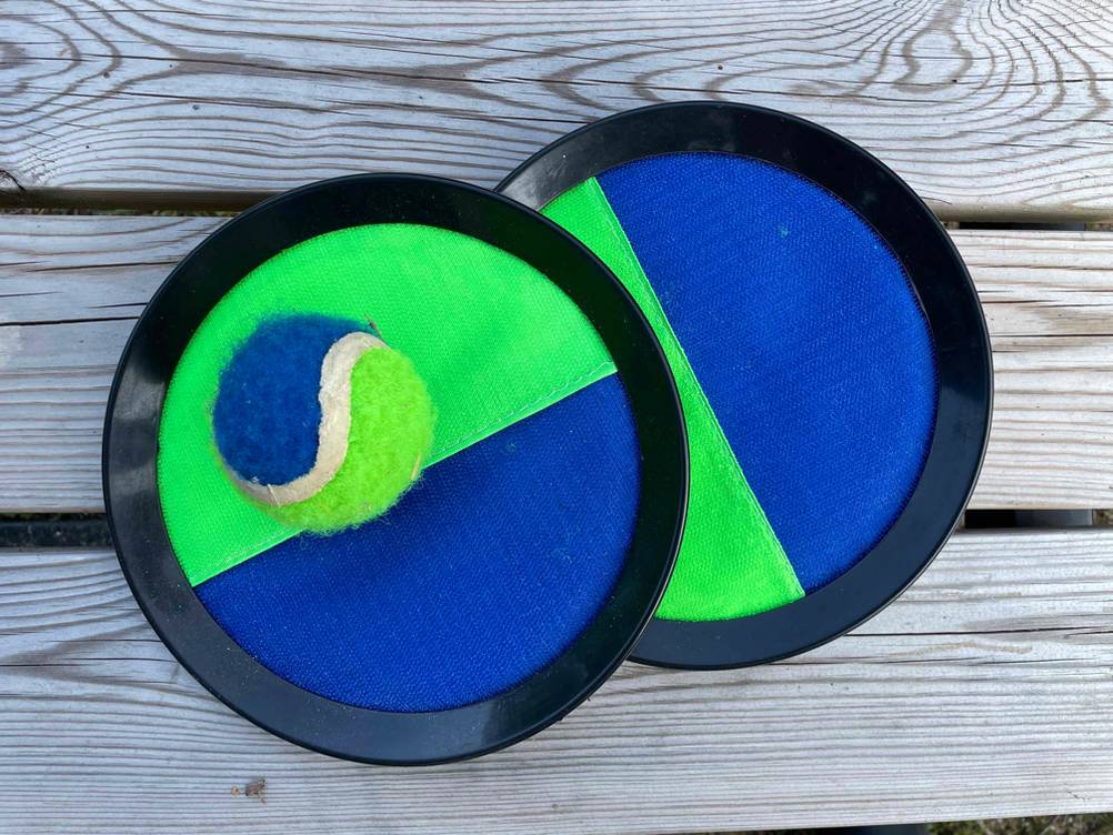 Klettballspiel-Test: Zwei Pads auf einer Holzfläche mit Ball.