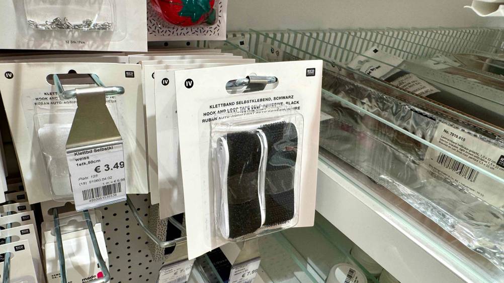 Mehrere des Klettband (selbstklebend) im Test hängen in einem Verkaufsregal neben anderen Produkten.