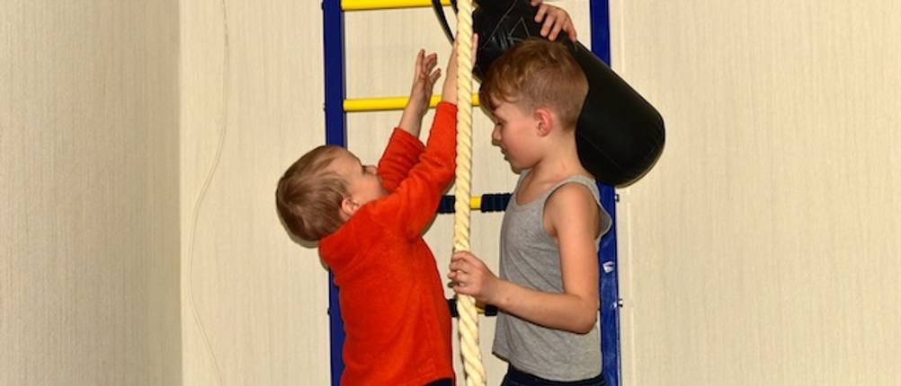 Indoor-Klettergerüst von zwei Jungen mit einer Kletterwand und einem Seil getestet.