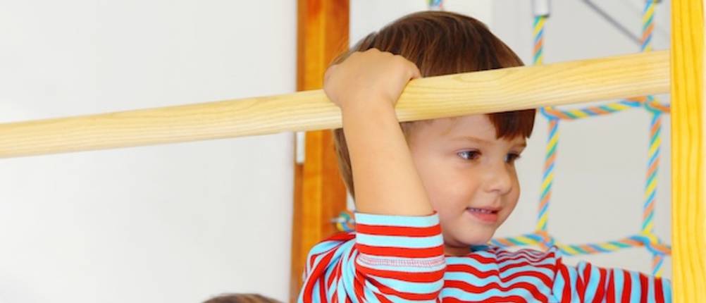 Klettergerüst Indoor getestet: Ein Junge klettert an einer Sprossenwand.