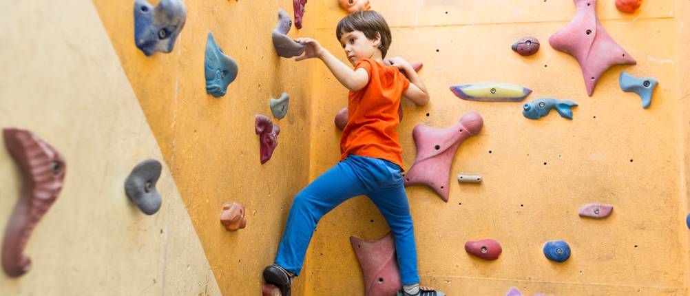 Klettergriffe-Test: Ein Junge klettert in einer Boulderhalle.