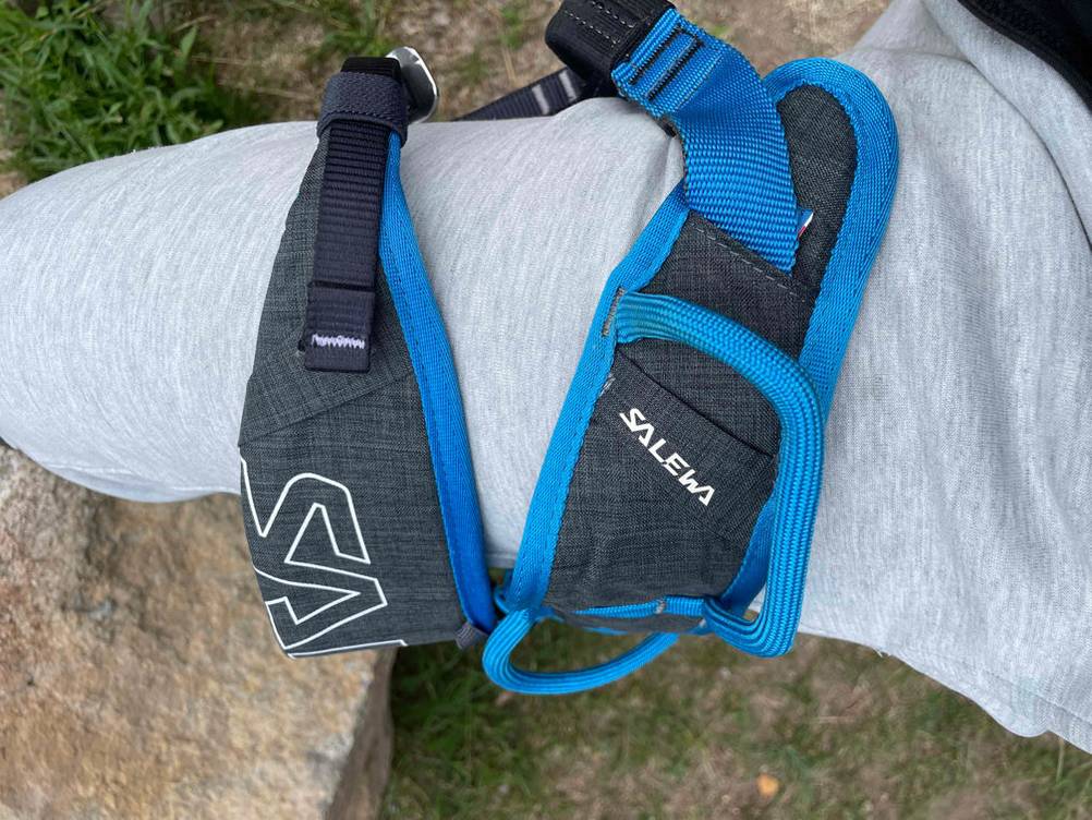 Klettergurt-Erwachsene-Test: Ein blau-schwarzer Klettergurt der Marke Salewa liegt auf einem Bein. 