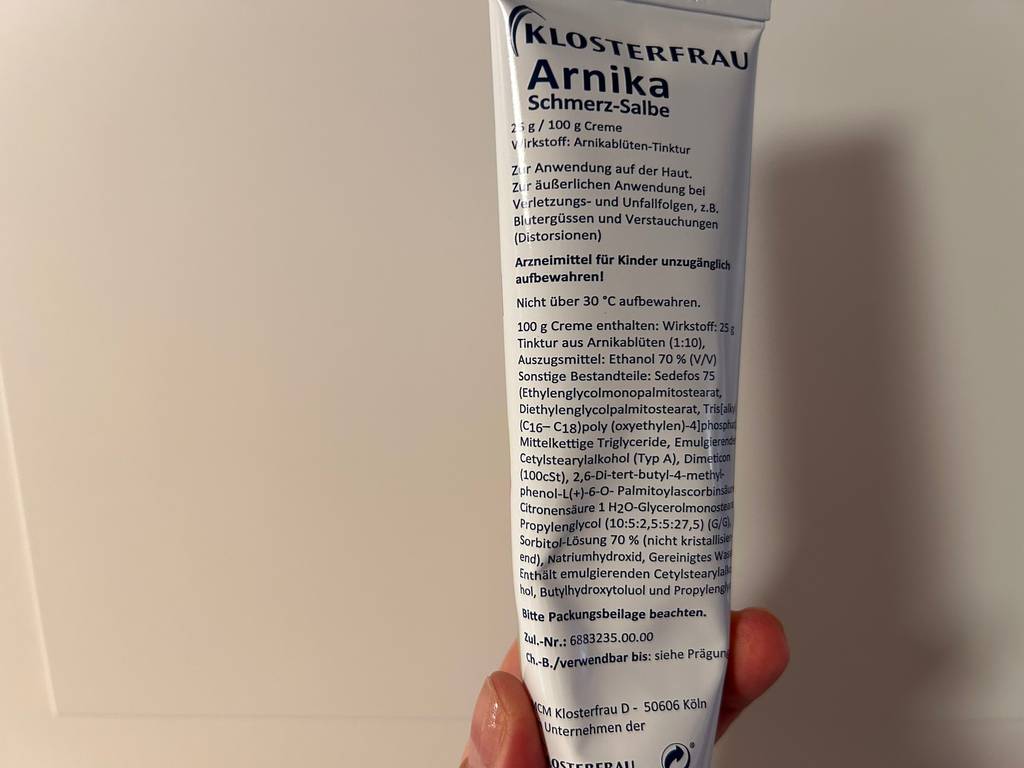 Auf der Rückseite einer Tube getesteter Arnika-Salbe stehen Informationen zum Hersteller und zum Produkt.