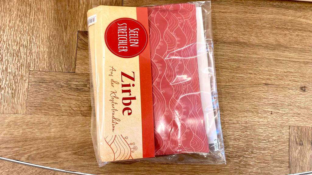 Zirbenkissen im Test: Verpacktes Zirbenkissen liegt auf Holzuntergrund.