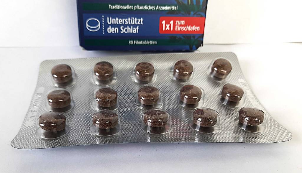 Eine Packung mit Baldrian-Dragees liegt zum testen vor der Verpackung.