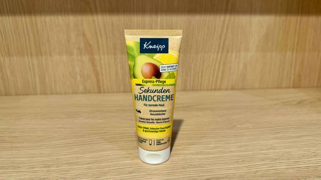 Eine Tube mit getesteter Kneipp-Handcreme steht auf einem Regal in Holzoptik.