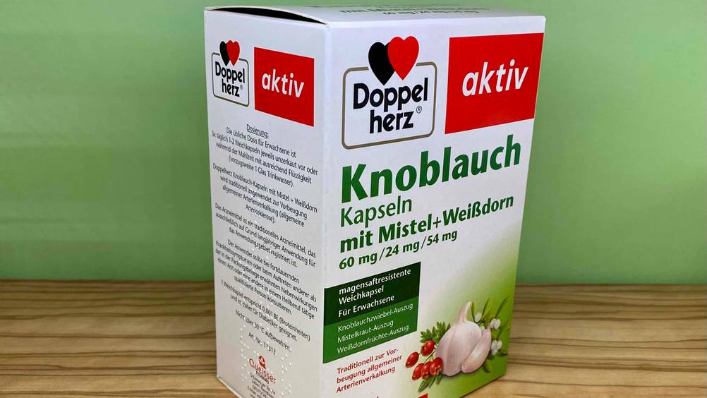 Seitenansicht einer Packung der getesteten Knoblauch-Kapseln vor einer grünen Wand.