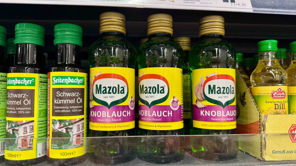 Mehrere Flaschen des getesteten Knoblauchöls in einem Verkaufsregal neben anderen Produkten.