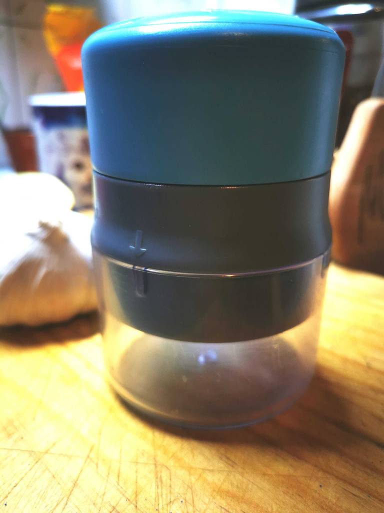Knoblauchschneider im Test: Ein Gerät steht auf einem Holzbrett.