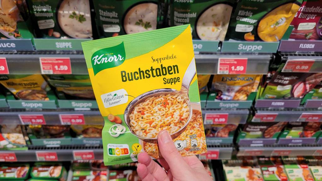 Eine Hand hält eine Packung Buchstaben-Instant-Suppe zum testen.