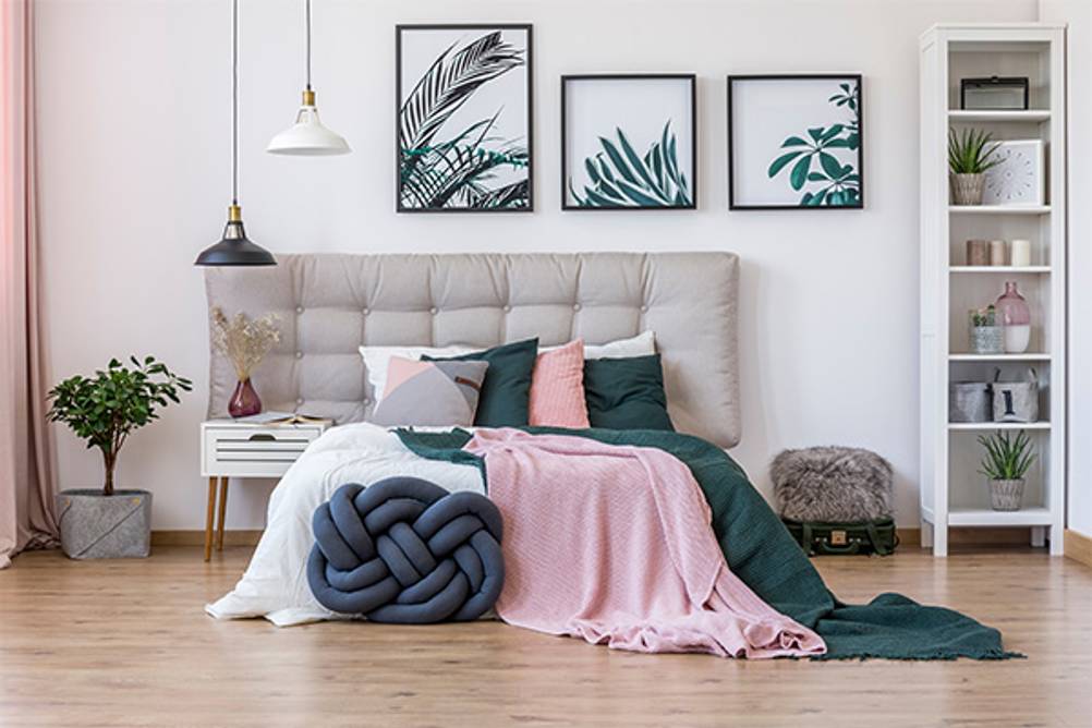 Knotenkissen im Test: Ein großes blaues Knotenkissen vor einem Bett.
