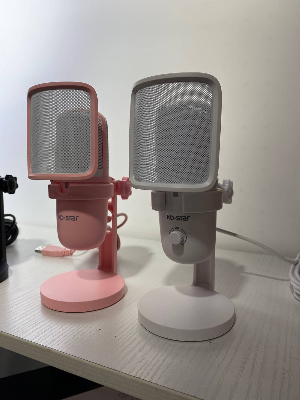 Im Test: Zwei USB Mikrofone von KO-Star in rosa und grau stehen in einem weißen Regal.