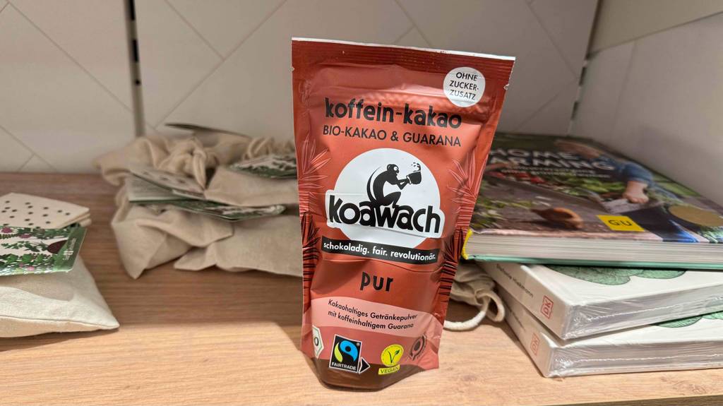 Koffein-Kakao im Test befindet sich in der braunen Tüte ohne Zucker-Zusatz auf einem Bücherregal.