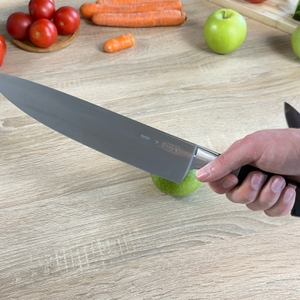 Das F.-Dick-1905-Messer wird über einem grünen Apfel gehalten. Die volle Klingenlänge ist sichtbar.