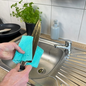 Das F.-Dick-1905-Kochmesser wird mit einem blauen Tuch an der Spüle abgetrocknet. Das Messer ist noch feucht.