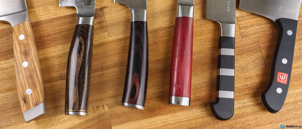 Verschiedene Messer liegen auf einem Holzbrett. Es sind die Griffe zu sehen.