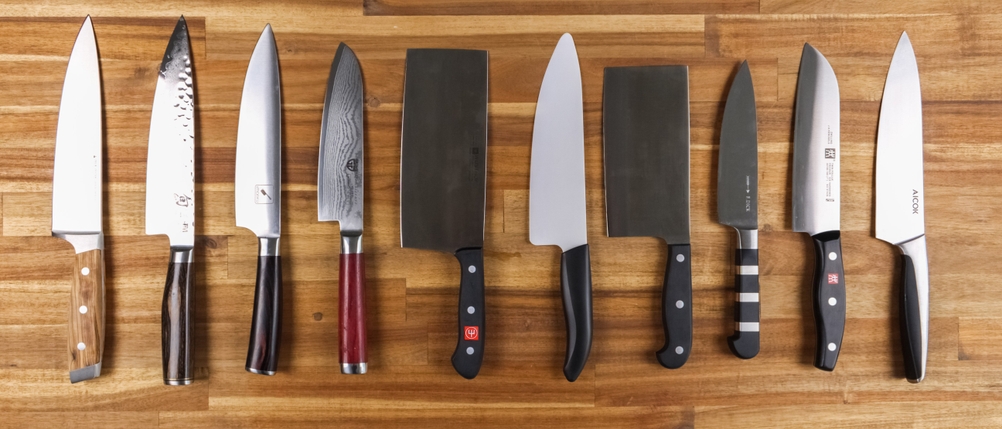 Zehn Messer liegen nebeneinander auf einem Holzuntergrund