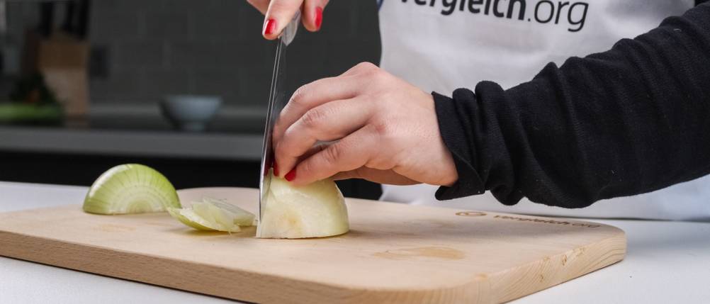 Eine Frau schneidet auf einem Küchenbrett eine Zwiebel