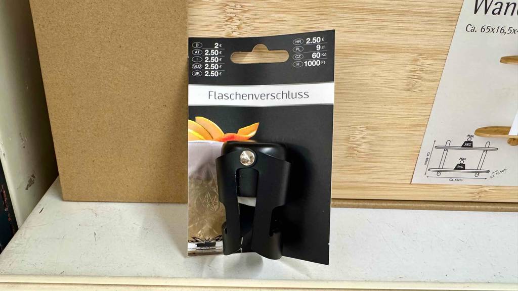 Im Test: Ein Flaschenverschluss in Schwarz lehnt mit seiner Kartonage an einem Holztisch.